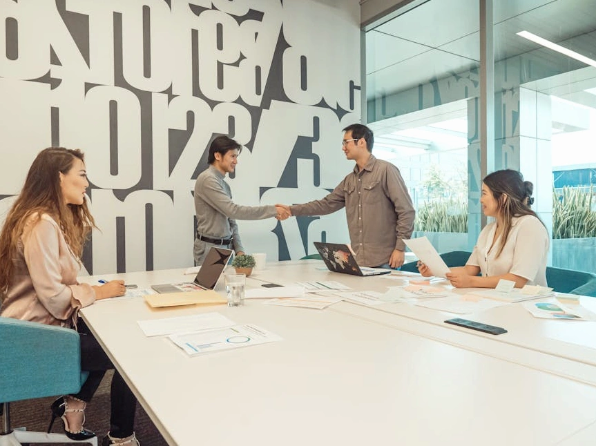 Profesionální konzultant podává ruku klientovi v moderní kanceláři.